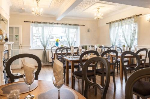 a dining room with tables and chairs and windows at Ty glyndwr Hotel in Bangor