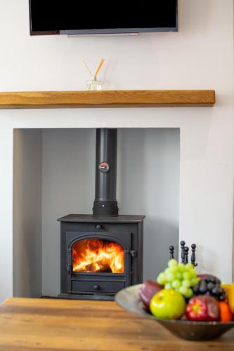 a stove with a plate of fruit in front of it at Woodcocks in Docking