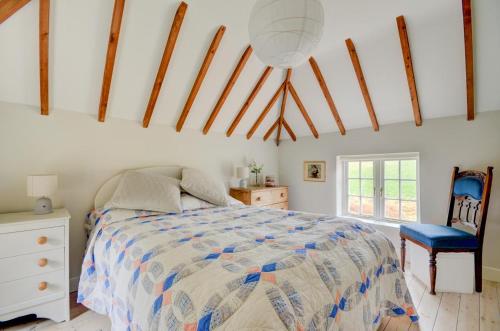 a bedroom with a bed and a blue chair at Aurora Cottage in Little Barningham