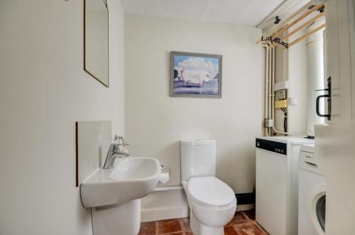 a white bathroom with a toilet and a sink at Aurora Cottage in Little Barningham