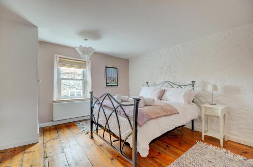 a bedroom with a bed with white sheets and a window at Tern Cottage in Wells next the Sea