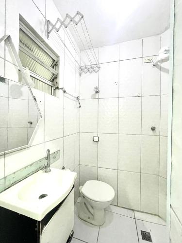 a white bathroom with a toilet and a sink at Alto Mar Studio in São Vicente