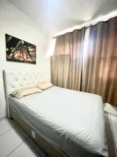 a bedroom with a white bed with a window at Alto Mar Studio in São Vicente