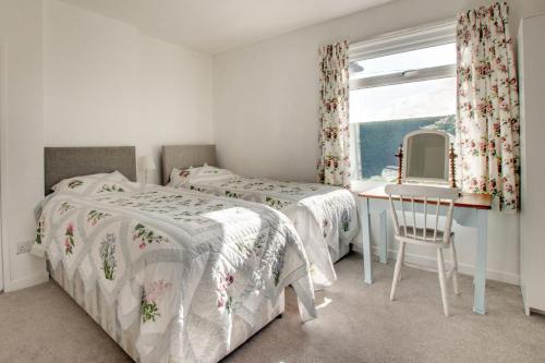 a bedroom with two beds and a desk and a window at Bolams Lodge in Ancroft