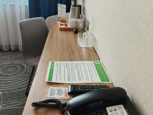 a table with a phone and a book on it at ibis styles Bolesławiec in Bolesławiec