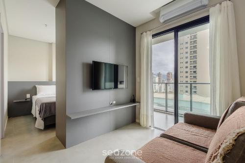 a bedroom with a bed and a tv and a window at Sua estadia exclusiva a poucos passos do Mar em Meia Praia - FFS in Perequê