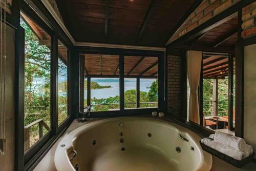 a large bath tub in a room with windows at Odoyá Cabana à beria-mar in Governador Celso Ramos