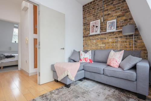 a living room with a couch and a brick wall at Stylish 1 Bedroom Apartment Near Northcote Road in London