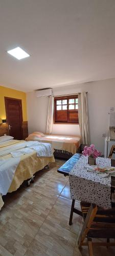 a bedroom with two beds and a table and a window at Porto do Sol - Chalé 07 in Pipa