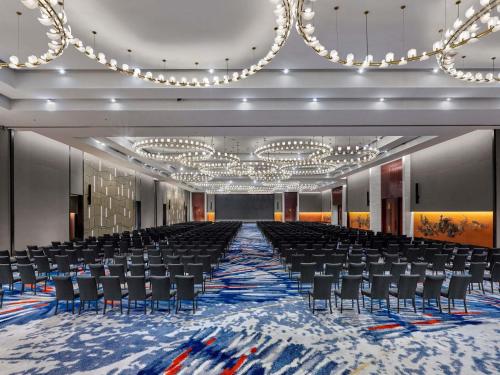 Habitación grande con sillas y un escenario con lámparas de araña. en Pullman Bandung Grand Central, en Bandung