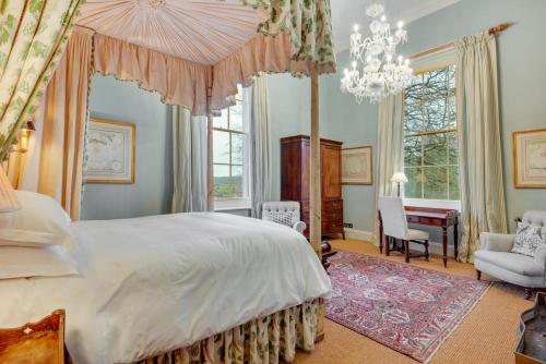 a bedroom with a large bed and a chandelier at The East Wing at Wolterton Hall in Itteringham