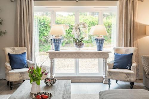 a living room with two chairs and a table with two lamps at Little Butts in Blakeney