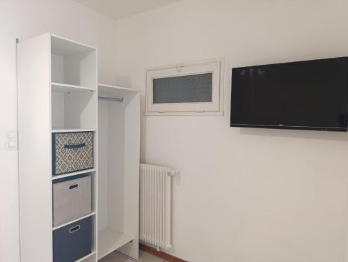 a room with a tv and a white wall at Cozy apartment, WiFi, garage, quiet city center in Ribérac