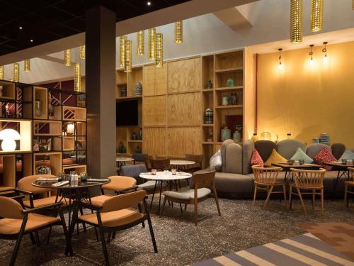 a restaurant with tables and chairs and a couch at Ibis Abdelmoumen Casa Centre in Casablanca