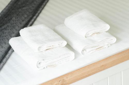 three white towels on a shelf in a bathroom at Olive Stays Apartment - 2 in Pristina