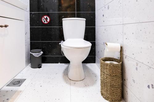 a white toilet in a bathroom with black tiles at Olive Stays Apartment - 2 in Pristina