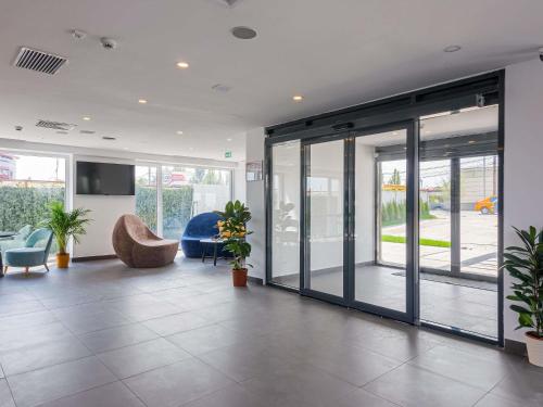 an office lobby with sliding glass doors and plants at Ibis Styles Bucharest Airport in Otopeni
