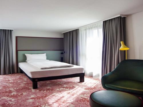 a bedroom with a bed and a couch and a chair at ibis Styles Klagenfurt am Woerthersee in Klagenfurt