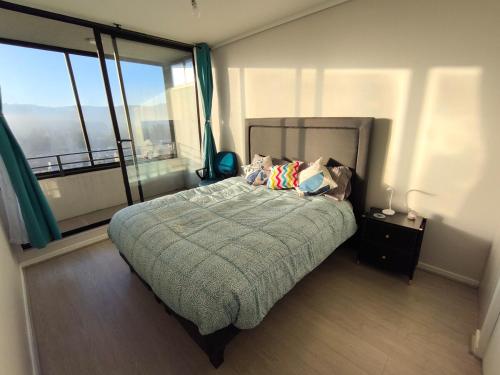 ein Schlafzimmer mit einem Bett und einem großen Fenster in der Unterkunft Departamento NUEVO de 2 dormitorios con terraza en Concepción in Concepción