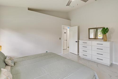 a white bedroom with a bed and a mirror at Fenced Yard, Game Room Family Home in Sebastian! in Sebastian