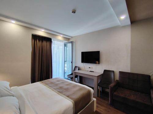 a hotel room with a bed and a desk and a television at PANORAMA Apartments BATUMI in Batumi