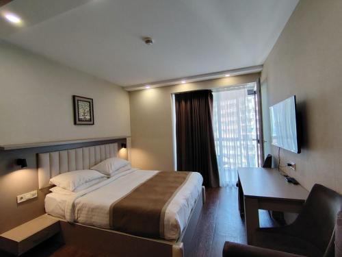 a hotel room with a bed and a desk and a computer at PANORAMA Apartments BATUMI in Batumi