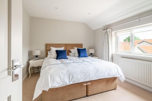 une chambre blanche avec un grand lit avec des oreillers bleus dans l'établissement Creake Cottage, à Burnham Market