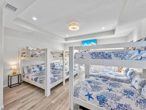 a room with three bunk beds with blue and white sheets at Seadreamz! Beachfront Heated Salt Pool! Sleep24! in Caplen