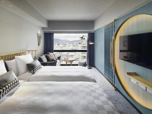 a hotel room with two beds and a flat screen tv at Mercure Kyoto Station in Kyoto