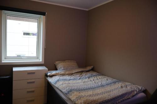 een slaapkamer met een bed, een dressoir en een raam bij Modern apartment on Kvaløya in Tromsø