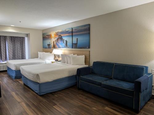 a hotel room with two beds and a couch at Days Inn & Suites by Wyndham Tampa/Raymond James Stadium in Tampa