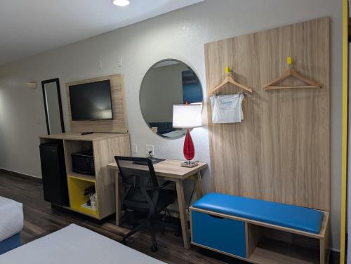 a room with a desk and a chair and a mirror at Days Inn & Suites by Wyndham Tampa/Raymond James Stadium in Tampa