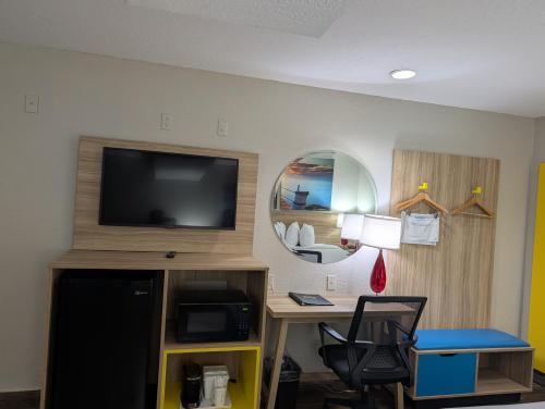 a room with a desk and a tv and a chair at Days Inn & Suites by Wyndham Tampa/Raymond James Stadium in Tampa