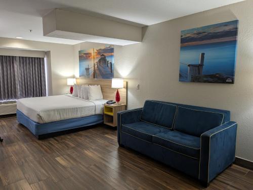a hotel room with a bed and a couch at Days Inn & Suites by Wyndham Tampa/Raymond James Stadium in Tampa