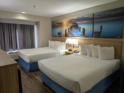a hotel room with two beds and a painting on the wall at Days Inn & Suites by Wyndham Tampa/Raymond James Stadium in Tampa