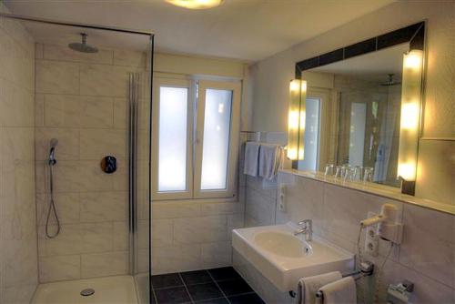 ein Bad mit einer Dusche, einem Waschbecken und einem Spiegel in der Unterkunft Breer S Hotel in Schwerte