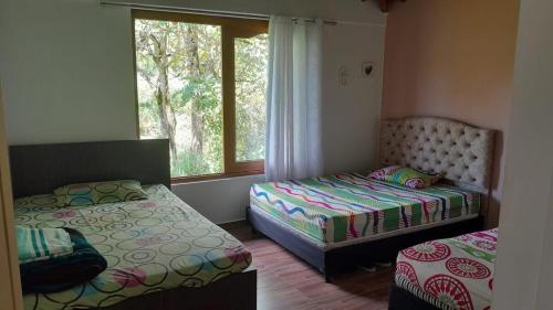 a bedroom with two beds and a window at Hermosa Casa de campo cerca a Yolombo, las partidas in Yolombó