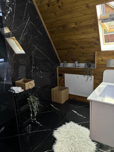a bathroom with a black marble floor and a sink at Riverside A-frame in Borşa