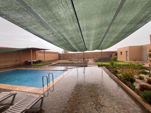 a swimming pool with a green umbrella over it at Relaxing & hammam Pool Villa, 40 min to Marrakech 