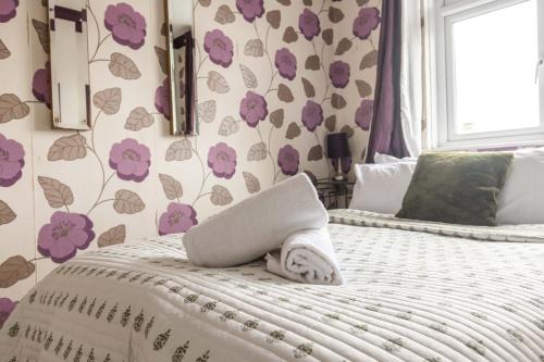 a bedroom with a bed with purple flowers on the wall at Ty glyndwr Hotel in Bangor