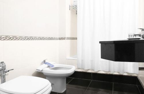 a white bathroom with a toilet and a shower curtain at Cyan Hotel de Las Americas in Buenos Aires