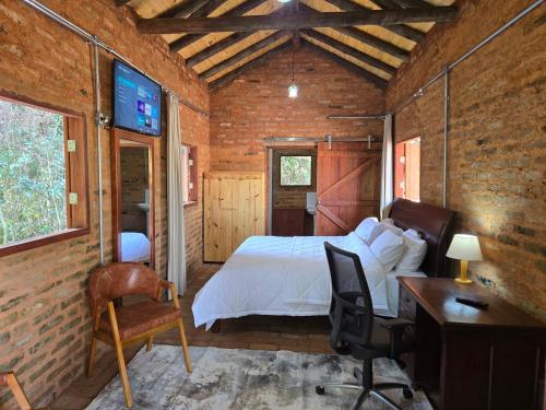 a bedroom with a bed and a desk and a tv at Cabana Rústica da Natureza in Jundiaí