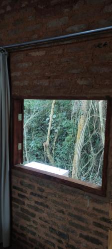 a window with a view of a forest through it at Cabana Rústica da Natureza in Jundiaí