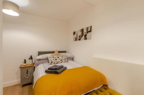 a bedroom with a bed with a yellow blanket on it at Princes Street Apartment in Hawick