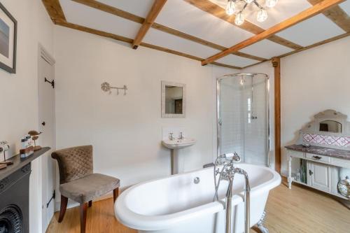 a bathroom with a white tub and a chair at Eastgate House Alnwick in Alnwick