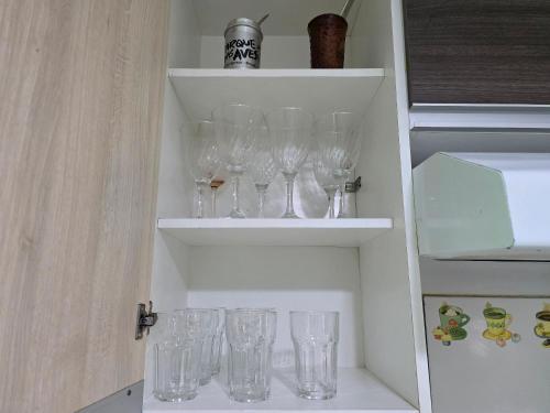 a row of wine glasses on shelves in a cabinet at Casa no Centro de Foz 2 quartos e 2 banheiros in Salto