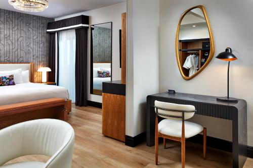 a bedroom with a bed and a desk with a mirror at Elan Hotel in Los Angeles