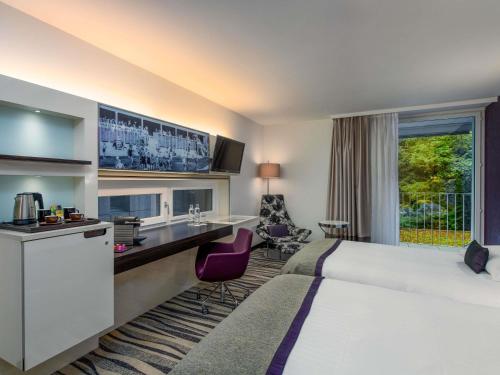 a hotel room with a large bed and a desk at Mövenpick Hotel Lausanne in Lausanne