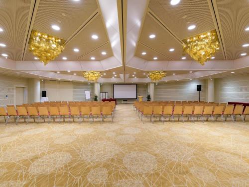a large room with chairs and a projection screen at Mövenpick Hotel Lausanne in Lausanne