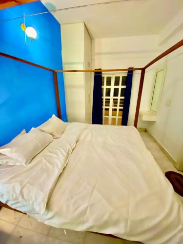 a white bed in a room with a blue wall at Villa Greek Baga 4Bhk Villa with private Pool & Kitchen in Calangute